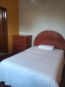 Schlafzimmer mit einem Bett mit einem Kopfteil aus Holz und einer Kommode in der Unterkunft Cáyamahue Guest House in Pucallpa