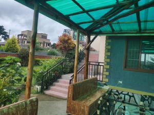 un banc en bois installé sur la terrasse couverte d'une maison dans l'établissement Alice Gardens and Campsite, à Entebbe