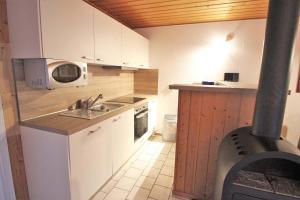 eine kleine Küche mit einer Spüle und einer Mikrowelle in der Unterkunft Möwe 104 in Mirow