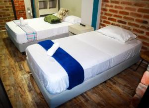 duas camas num quarto com uma parede de tijolos em Finca Hotel el Diamante em Calarcá