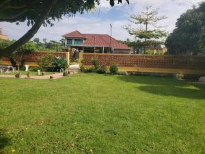 a fence in front of a house with a yard at Alice Gardens and Campsite in Entebbe
