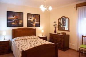 1 dormitorio con 1 cama y algunas fotos en la pared en Casa Espaçosa perto de Angra, en Angra do Heroísmo