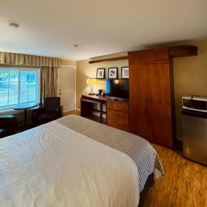 a hotel room with a white bed and a desk at Coach House Inn in Tobermory