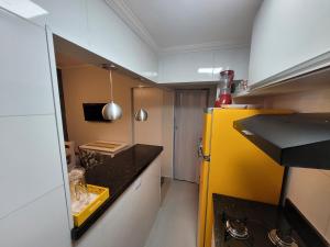 uma cozinha com um frigorífico amarelo e uma bancada preta em Apartamento pé na areia na Praia Grande