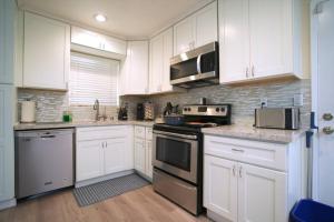 uma cozinha com armários brancos e electrodomésticos de aço inoxidável em Cozy 3BR: AC & Great Location em San José