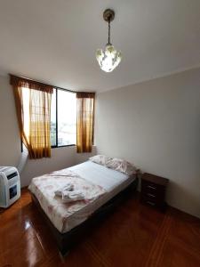 - une chambre avec un lit et un lustre dans l'établissement Departamentos de la Costa, à Machala
