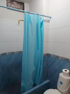 y baño con cortina de ducha azul y aseo. en Departamentos de la Costa, en Machala