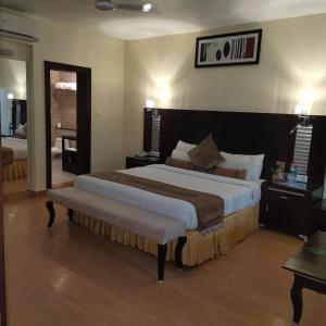 Un dormitorio con una cama grande y un banco. en The Red Maple Mashal, en Indore