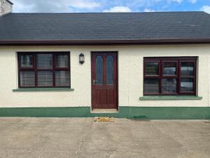 a house with a brown door and two windows at Thornstown Gate Cottage in Portglenone