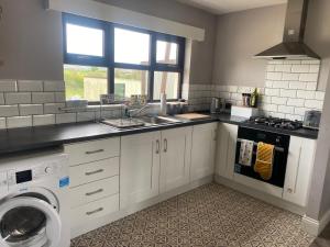 a kitchen with a sink and a washing machine at Thornstown Gate Cottage in Portglenone +5 photos