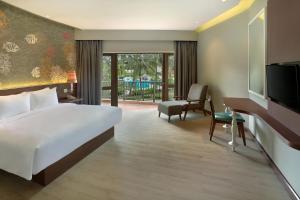 マナドにあるManado Tateli Resort and Conventionのベッド、デスク、テレビが備わるホテルルームです。