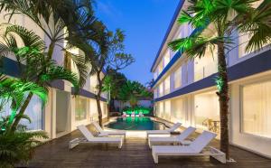 a swimming pool with white lounge chairs next to a building at Coast Boutique Hotel in Kuta