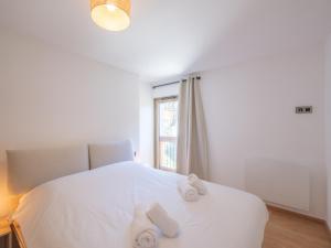 um quarto com uma cama branca e toalhas em Appartement Huez, 3 pièces, 4 personnes - FR-1-645-72 em LʼHuez