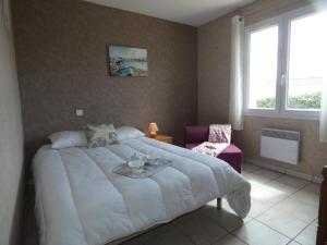 a bedroom with a large white bed and a chair at Maison lumineuse avec jardin - 4 personnes - FR-1-540-286 in Notre-Dame-de-Monts