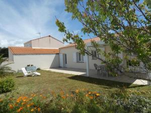 a white house with a yard with chairs and flowers at Maison lumineuse avec jardin - 4 personnes - FR-1-540-286 in Notre-Dame-de-Monts