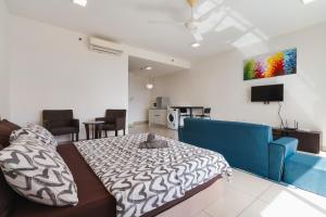 uma sala de estar com uma cama e um sofá azul em NETFLIX STUDIO @ TREFOIL SETIA CITY em Setia Alam