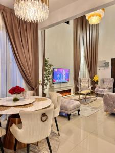 a living room with a table and chairs and a tv at Resthouse Asyura in Melaka