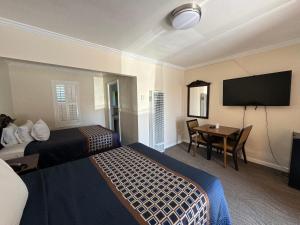 a hotel room with two beds and a table and a tv at Tamalpais Motel in Mill Valley