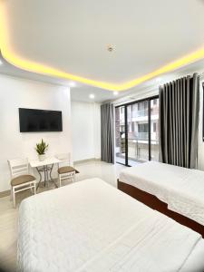 una habitación de hotel con 2 camas y una mesa con sillas en KAMI HOTEL en Phan Rang