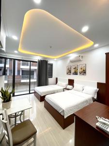 1 dormitorio con 2 camas, mesa y escritorio en KAMI HOTEL en Phan Rang