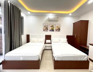 2 camas en una habitación con paredes blancas en KAMI HOTEL, en Phan Rang
