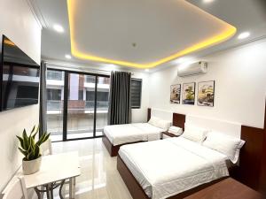 una camera d'albergo con due letti e un divano di KAMI HOTEL a Phan Rang-Tháp Chàm