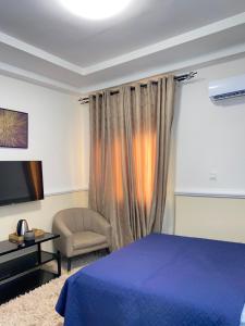 a bedroom with a blue bed and a chair at EL Apartment in East Legon