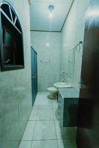 a white bathroom with a toilet and a sink at Pousada São Benedito in Santo Antônio do Pinhal