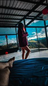 a woman standing on a bed in front of a window at SUITE STARS in Latacunga