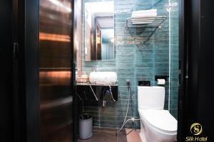 La salle de bains est pourvue de toilettes et d'un mur carrelé vert. dans l'établissement Silk Hotel near Tan Son Nhat Airport, à Hô-Chi-Minh-Ville