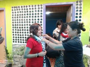 een vrouw die een andere vrouw helpt haar das vast te binden bij Dsd Bomzon Homestay in Darjeeling
