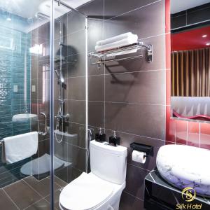 a bathroom with a toilet and a glass shower at Silk Hotel near Tan Son Nhat Airport in Ho Chi Minh City