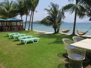 Badladz Beach and Dive Resort في بويرتو غاليرا: صف من الكراسي والمراجيح على الشاطئ