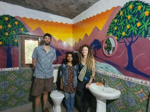 un groupe de personnes debout dans une salle de bains avec une fresque murale dans l'établissement Hobo Huts, à Panuānaula