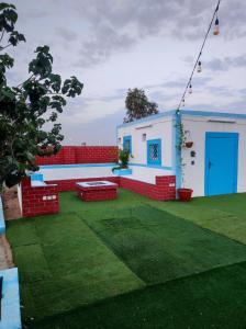 a house with a green yard with a blue door at استراحه ابو فهد in Al Qurayn