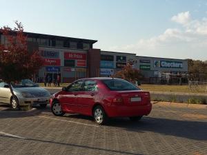 un coche rojo estacionado frente a una tienda en Kgopolo Homestay, en Modimolle