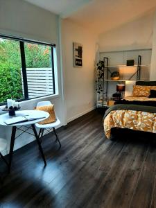 een slaapkamer met een bed, een tafel en een raam bij Tree View Studio in Tauranga