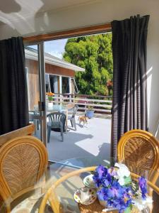 a glass table with chairs and a dog on a patio at Garden View on Hone Heke Kerikeri in Kerikeri