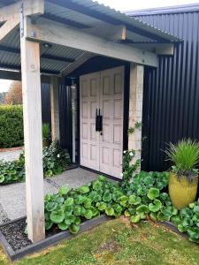 a garage with a white door and a bunch of plants at Tree View Studio in Tauranga