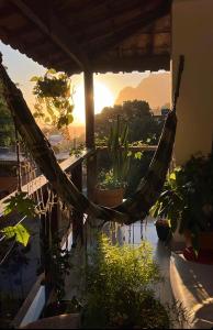 una hamaca en un balcón con plantas y puesta de sol en House TT do Vidigal, en Río de Janeiro