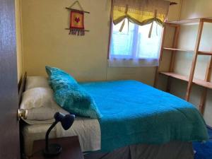 1 dormitorio con cama con sábanas azules y ventana en Casa Cabaña Oro Rayado Puerto Varas, en Puerto Varas