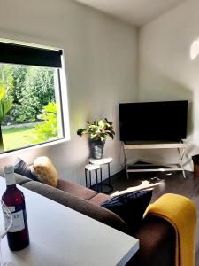een woonkamer met een bank en een flatscreen-tv bij Tree View Studio in Tauranga