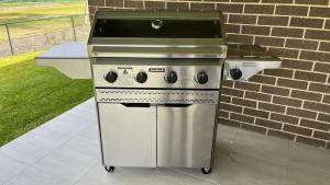 Una estufa de acero inoxidable y una parrilla junto a una pared de ladrillos. en Fairway to Heaven, en Sussex Inlet