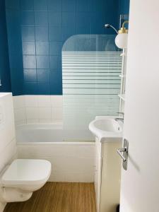 a bathroom with a toilet and a tub and a sink at Appartement cosy aux portes de Paris in Montreuil