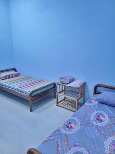 a blue room with two beds and a chair at Homestay Haji Noor in Tanah Merah