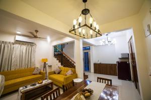 a living room with a yellow couch and a table at Villa Cozy - Luxury Plunge Pool Villa in South Goa in Benaulim