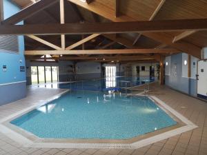 a large swimming pool in a building with a wooden ceiling at Victoria Cottage in Amble