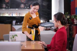 a woman is pouring a drink into a glass at Merlynn Park Hotel in Jakarta
