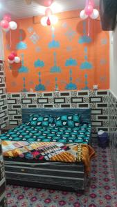a bed in a room with an orange wall at Kanha ji Divine dham 89799Vrindavan12972, free pick up also taxi and Activa rent in Mathura +26 photos
