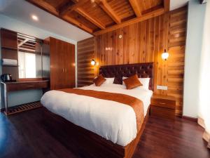 1 dormitorio con 1 cama grande y paredes de madera en Vista Resort, Manali - centrally Heated & Air cooled luxury rooms, en Manali